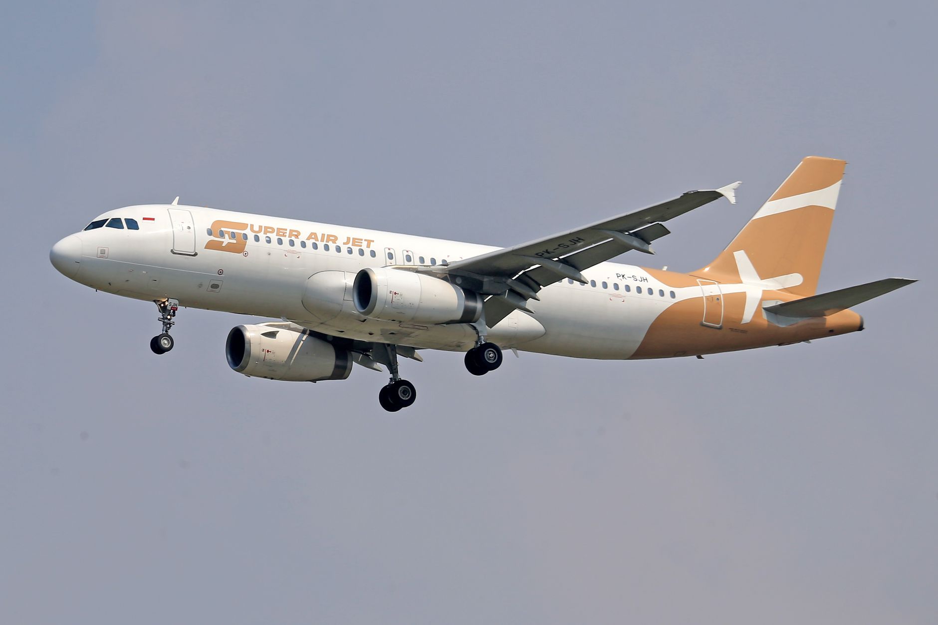 Pesawat Airbus A320-200 Super Air Jet yang ditangkap saat terbang di langit cerah, menampilkan desainnya.