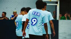 Sekelompok pria muda bermain sepak bola di lapangan terbuka di Ciudad de México, menunjukkan semangat tim.