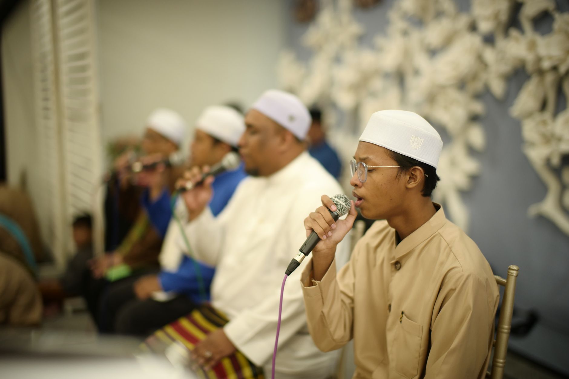 Sekelompok pria Muslim bernyanyi menggunakan mikrofon di acara budaya di Kuala Lumpur.