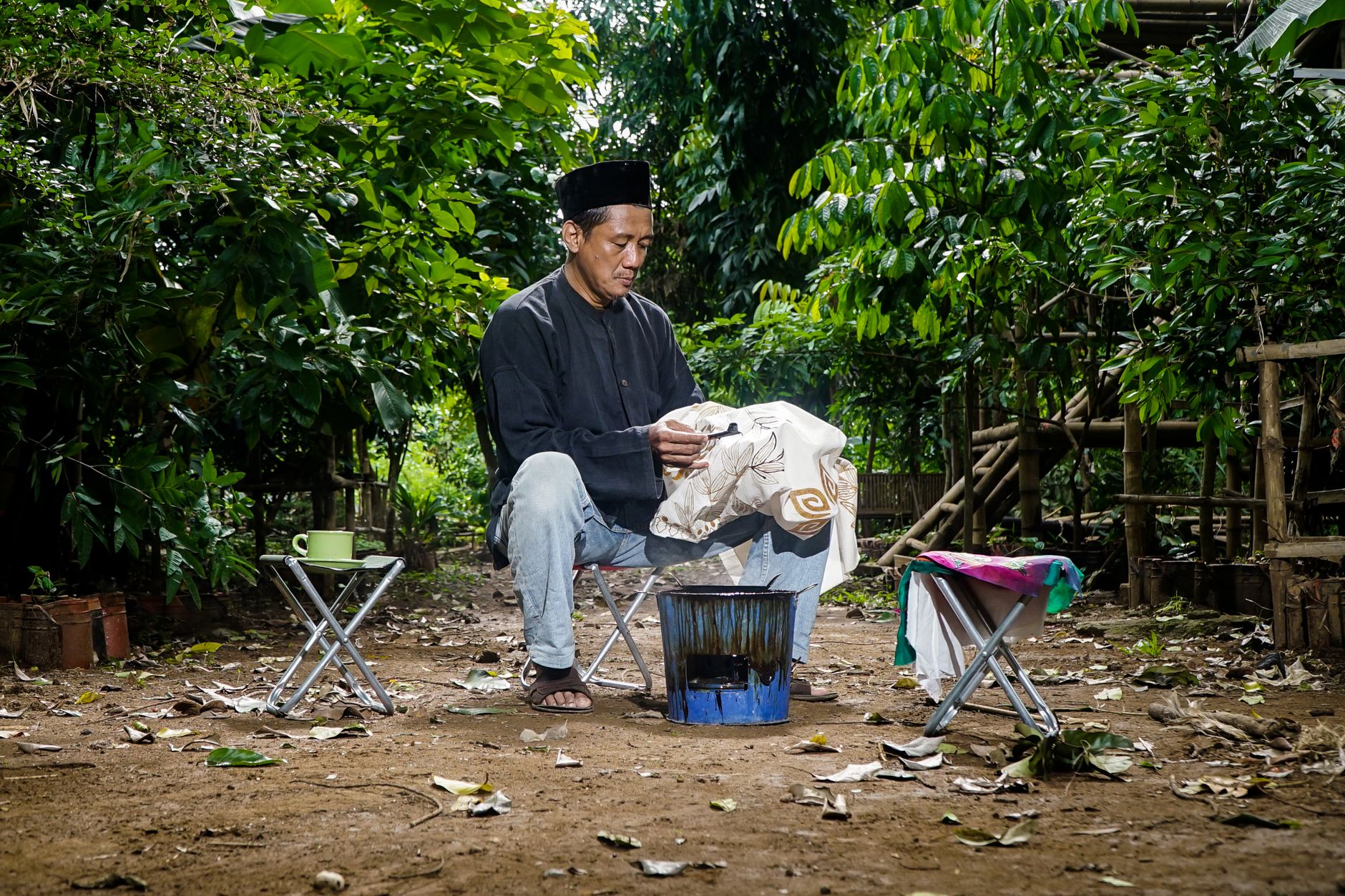Seorang pria dewasa membuat batik menggunakan teknik tradisional di luar ruangan.