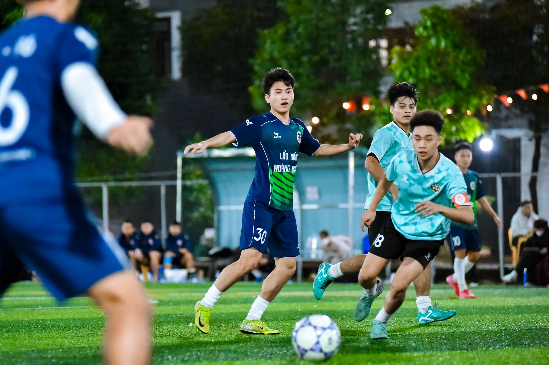 Pertandingan sepak bola yang penuh warna dengan pemain yang beraksi di lapangan lokal di Hanoi, Vietnam.