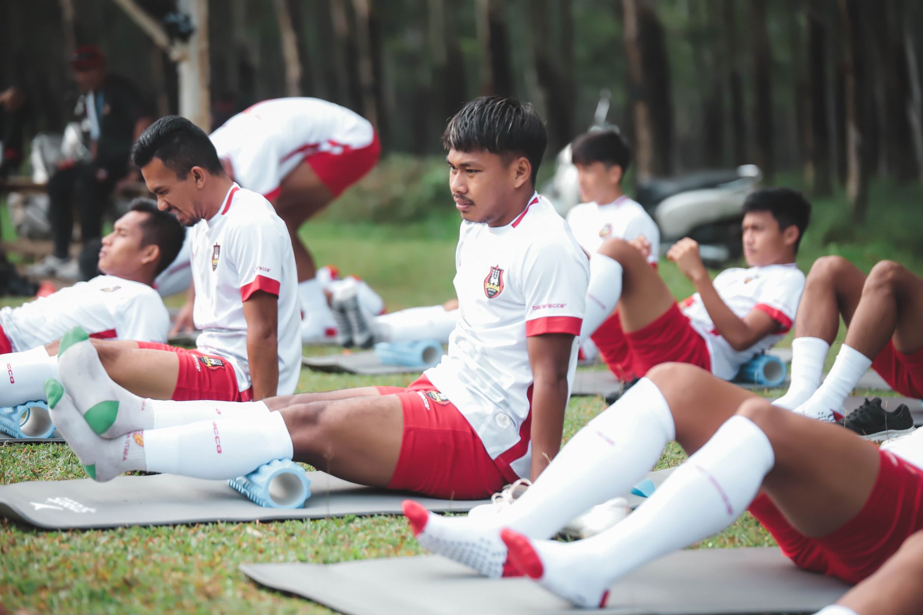 Pemain sepak bola dalam sesi latihan melakukan peregangan di lapangan di Jakarta.