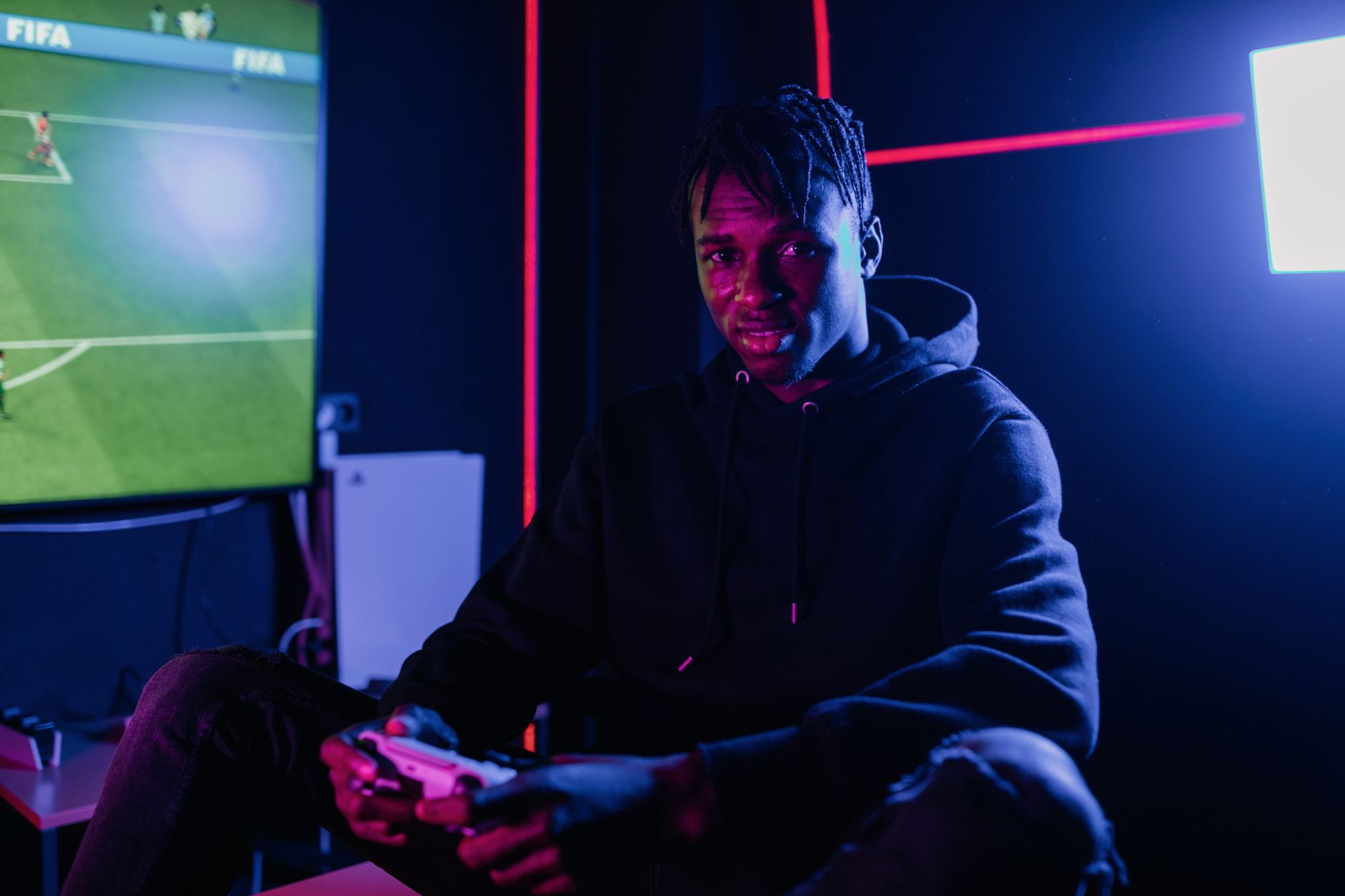 Seorang pria yang bermain video game di malam hari di ruangan dengan lampu neon, tenggelam dalam kesenangan dan hiburan.