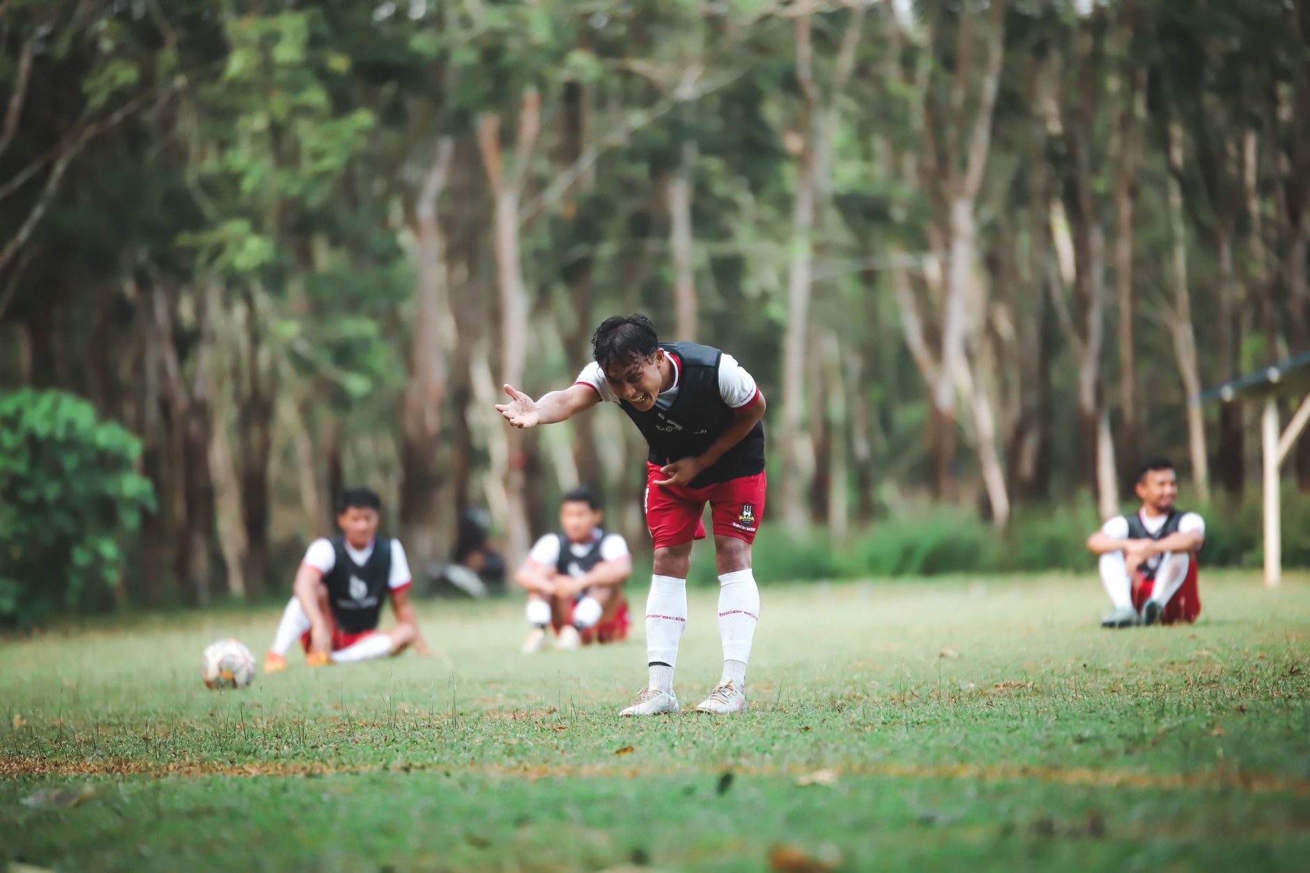 Pemain sepak bola muda berlatih di lapangan yang berdampingan, fokus pada kerja tim dan keterampilan.