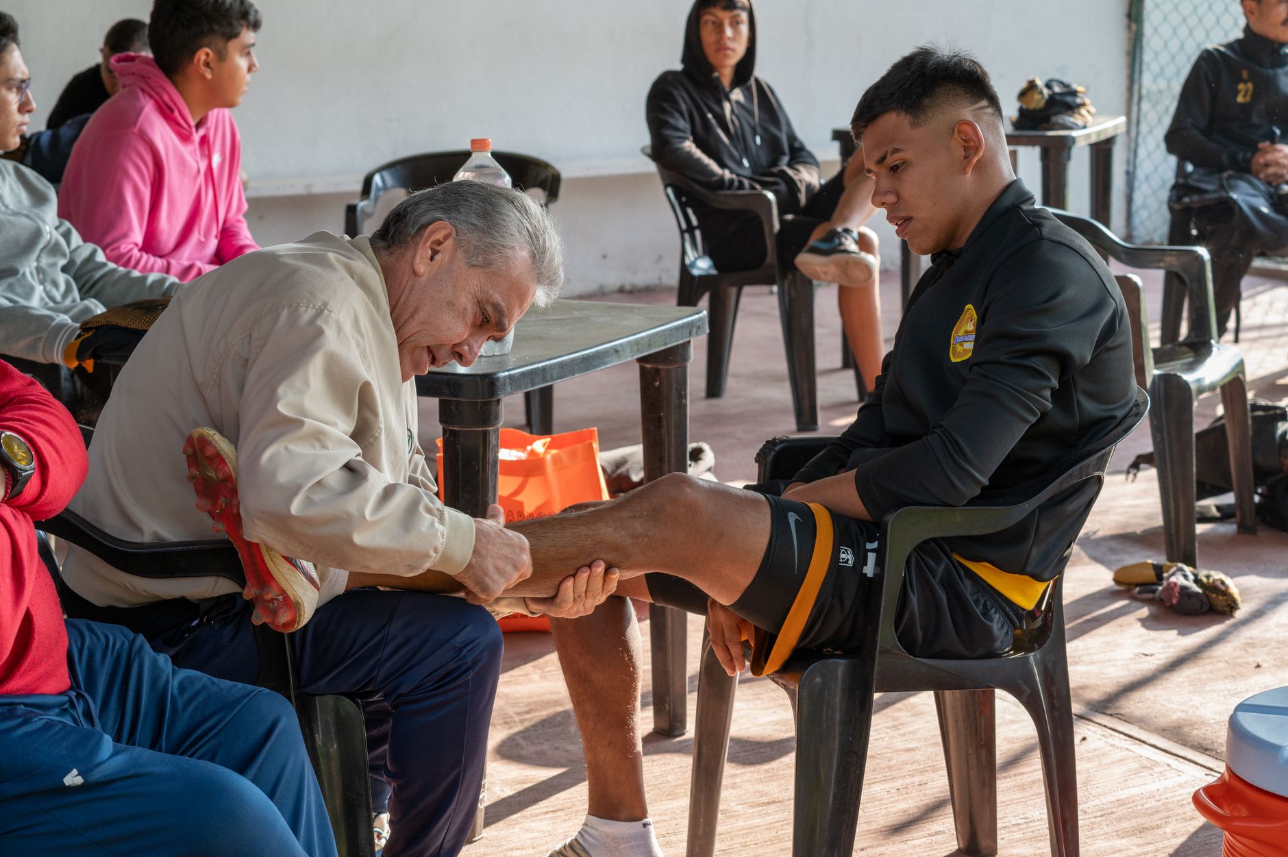 Seorang pelatih merawat cedera pemain sepak bola, memberikan dukungan dan perawatan selama latihan.