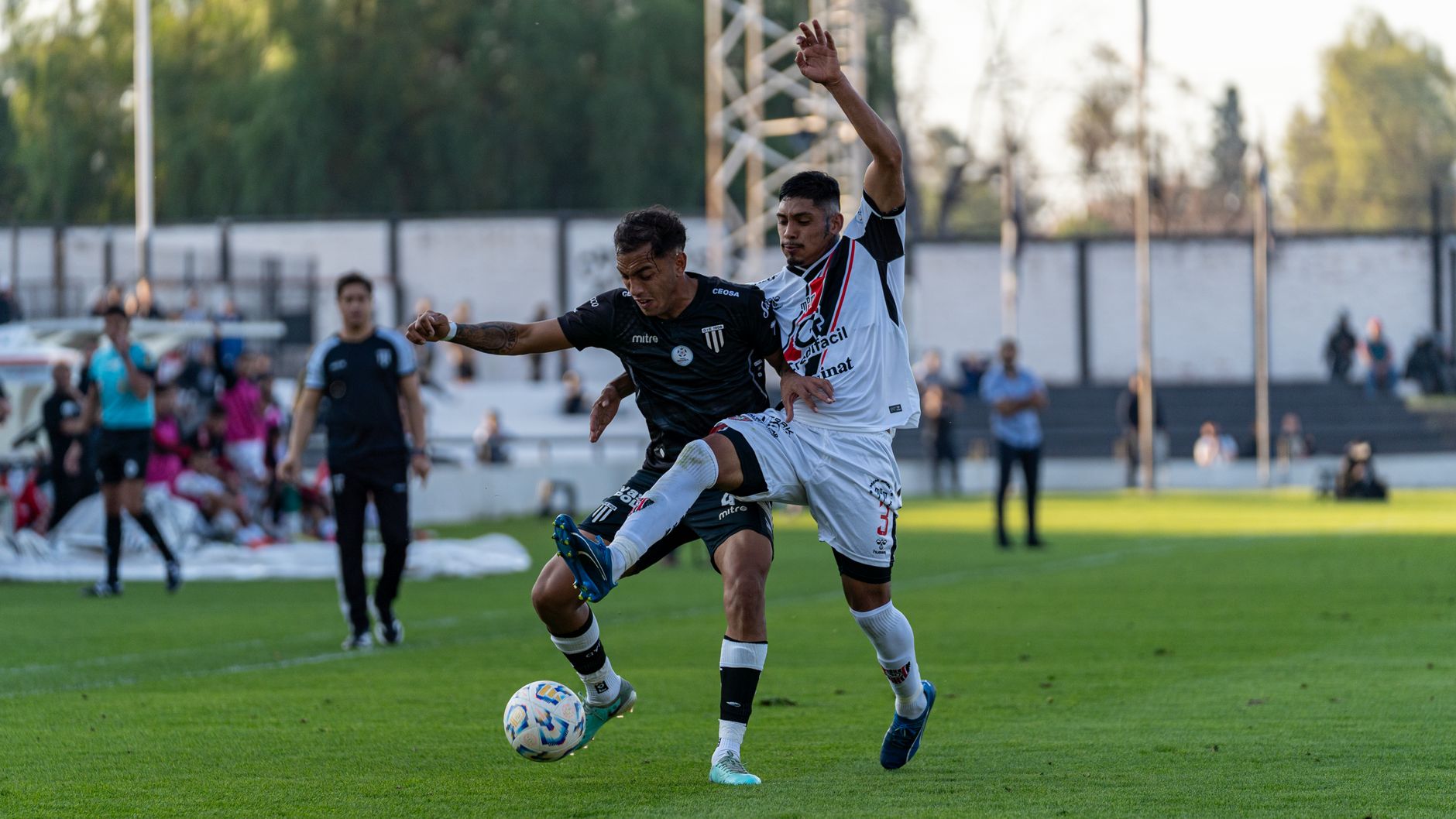 Pengambilan gambar dinamis yang menangkap dua pemain sepak bola yang bersaing memperebutkan bola selama pertandingan sepak bola di luar ruangan.