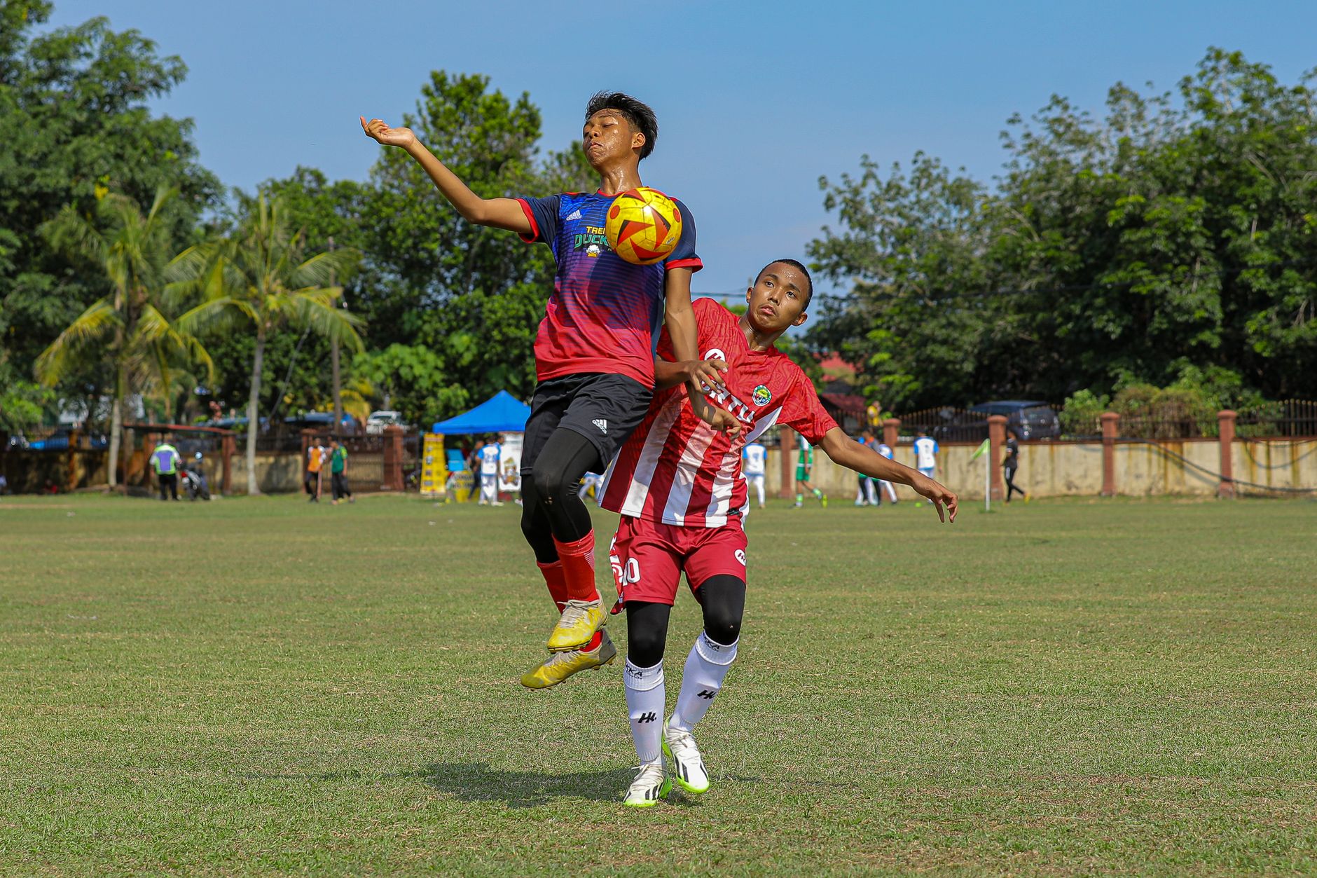 Dua pemain sepak bola muda bersaing ketat untuk merebut bola di lapangan terbuka.