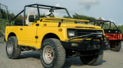 Kendaraan off-road kuning cerah diparkir di pantai berpasir, ideal untuk perjalanan petualangan.