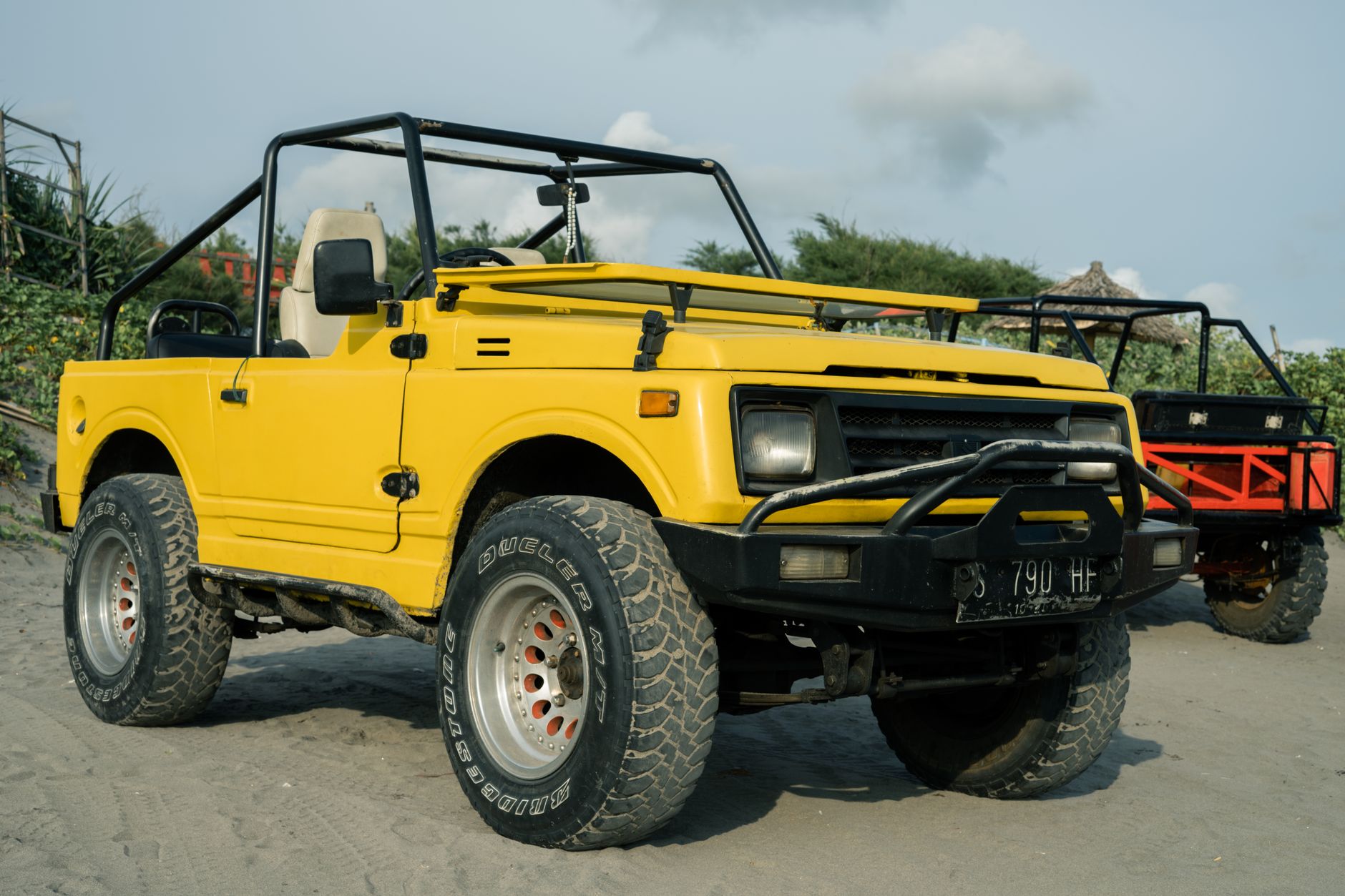 Kendaraan off-road kuning cerah diparkir di pantai berpasir, ideal untuk perjalanan petualangan.
