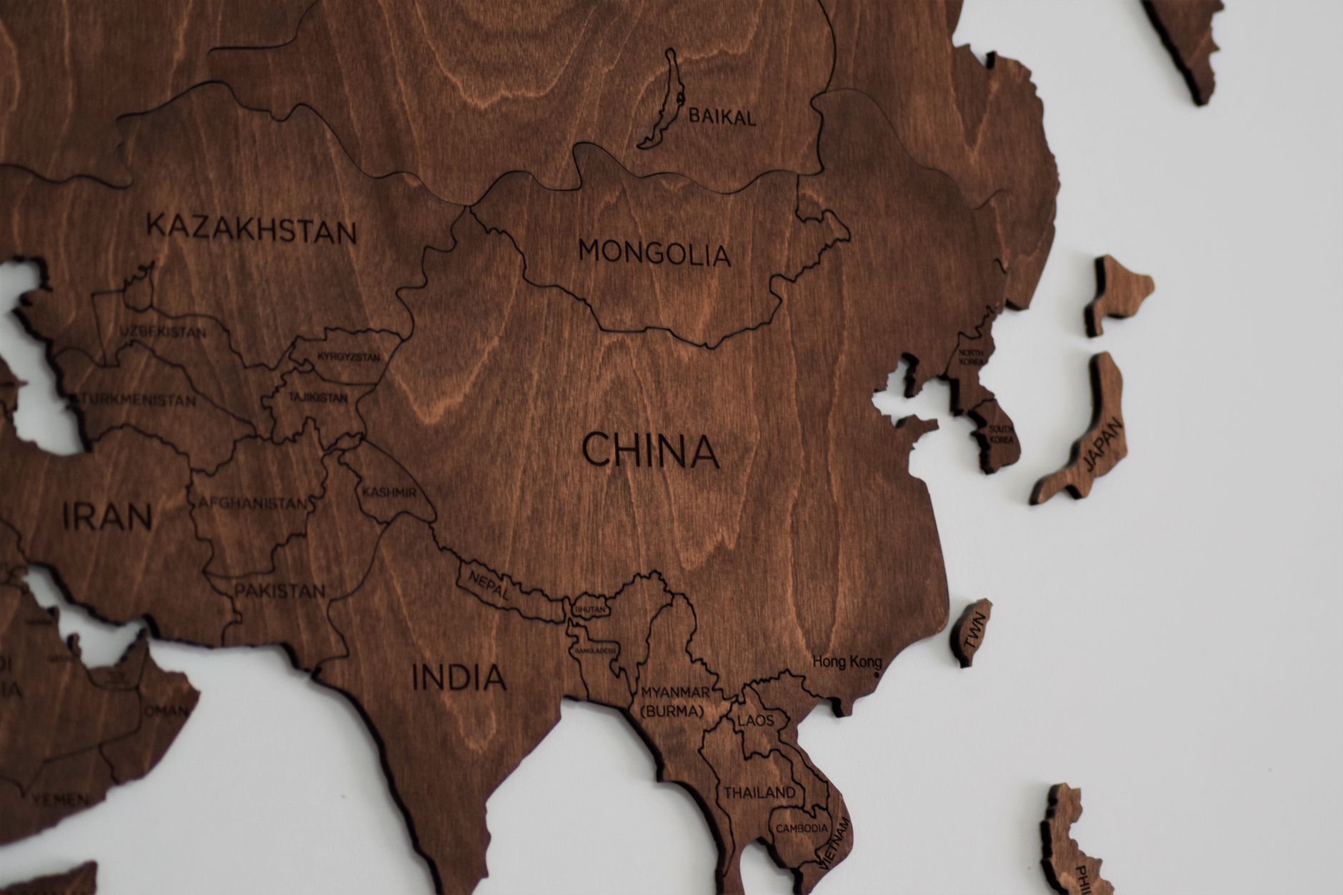 Tampilan dekat peta kayu yang detail dari Asia, menunjukkan negara-negara seperti China dan India.