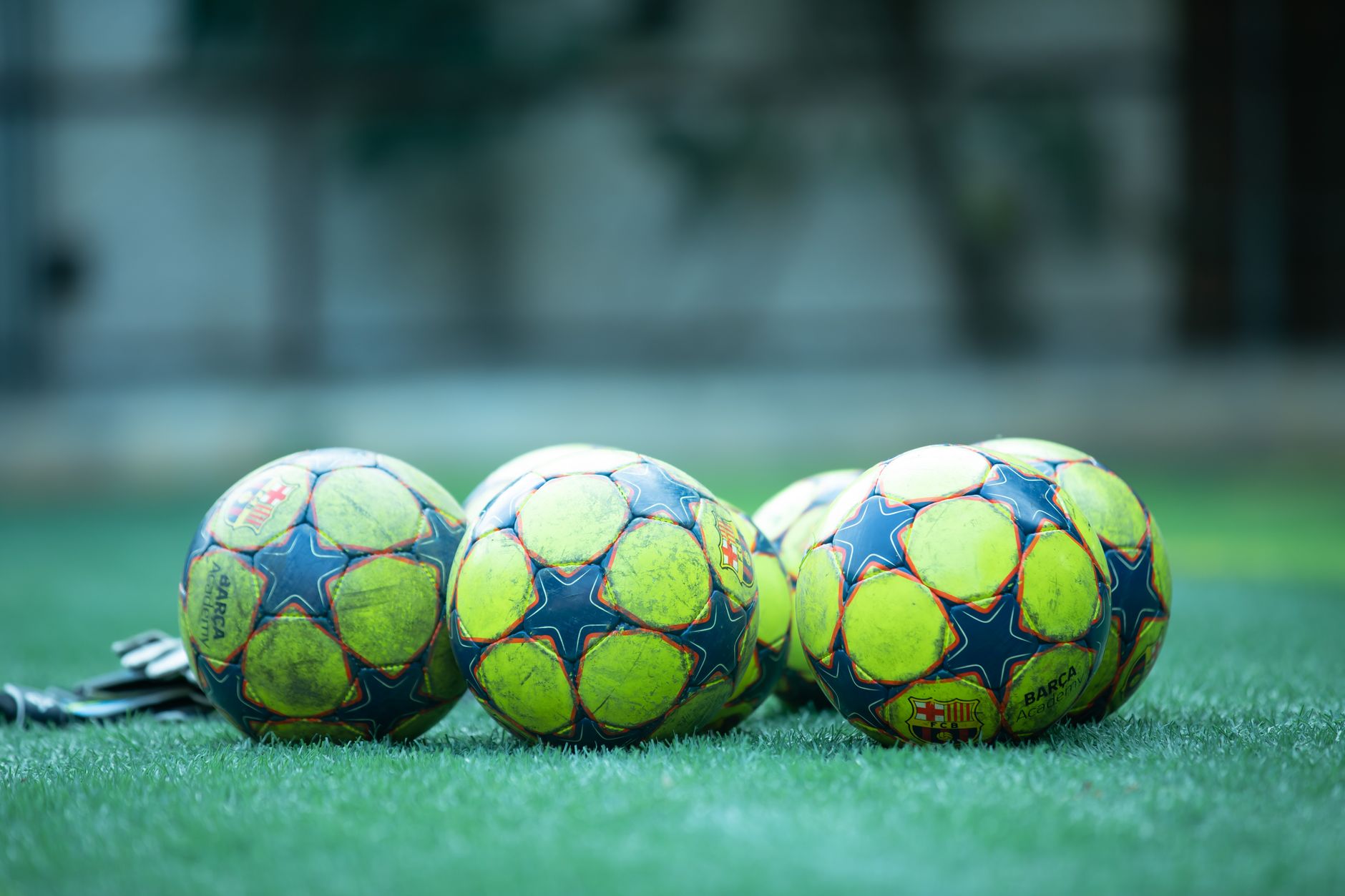 Empat bola sepak yang cerah beristirahat di lapangan rumput hijau.