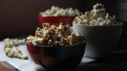 Pemandangan nyaman dengan popcorn dalam mangkuk di atas meja kayu, sempurna untuk suasana malam menonton film.