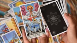 Dekatkan tangan yang memegang kartu tarot dengan kartu Penghakiman yang ditampilkan secara mencolok.