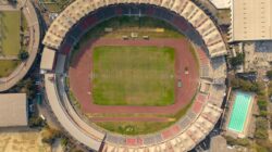 Pemandangan dari atas stadion sepak bola nasional dengan lanskap perkotaan di sekitarnya.