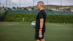 Pelatih berpengalaman memegang bola sepak saat latihan sepak bola di luar ruangan.