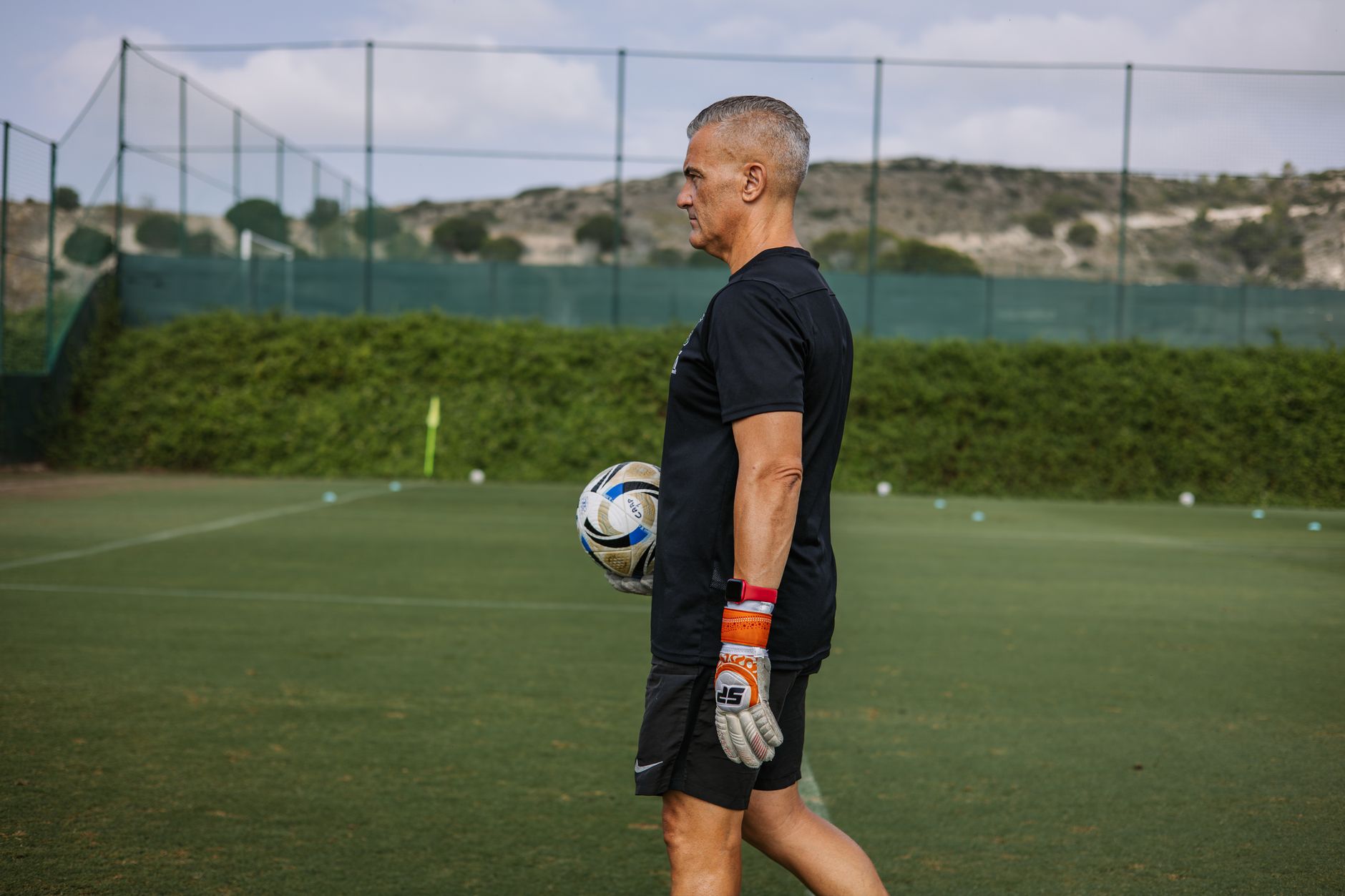 Pelatih berpengalaman memegang bola sepak saat latihan sepak bola di luar ruangan.
