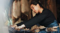Seorang wanita dengan terampil menenun kain tradisional di atas alat tenun di Banten, Indonesia.