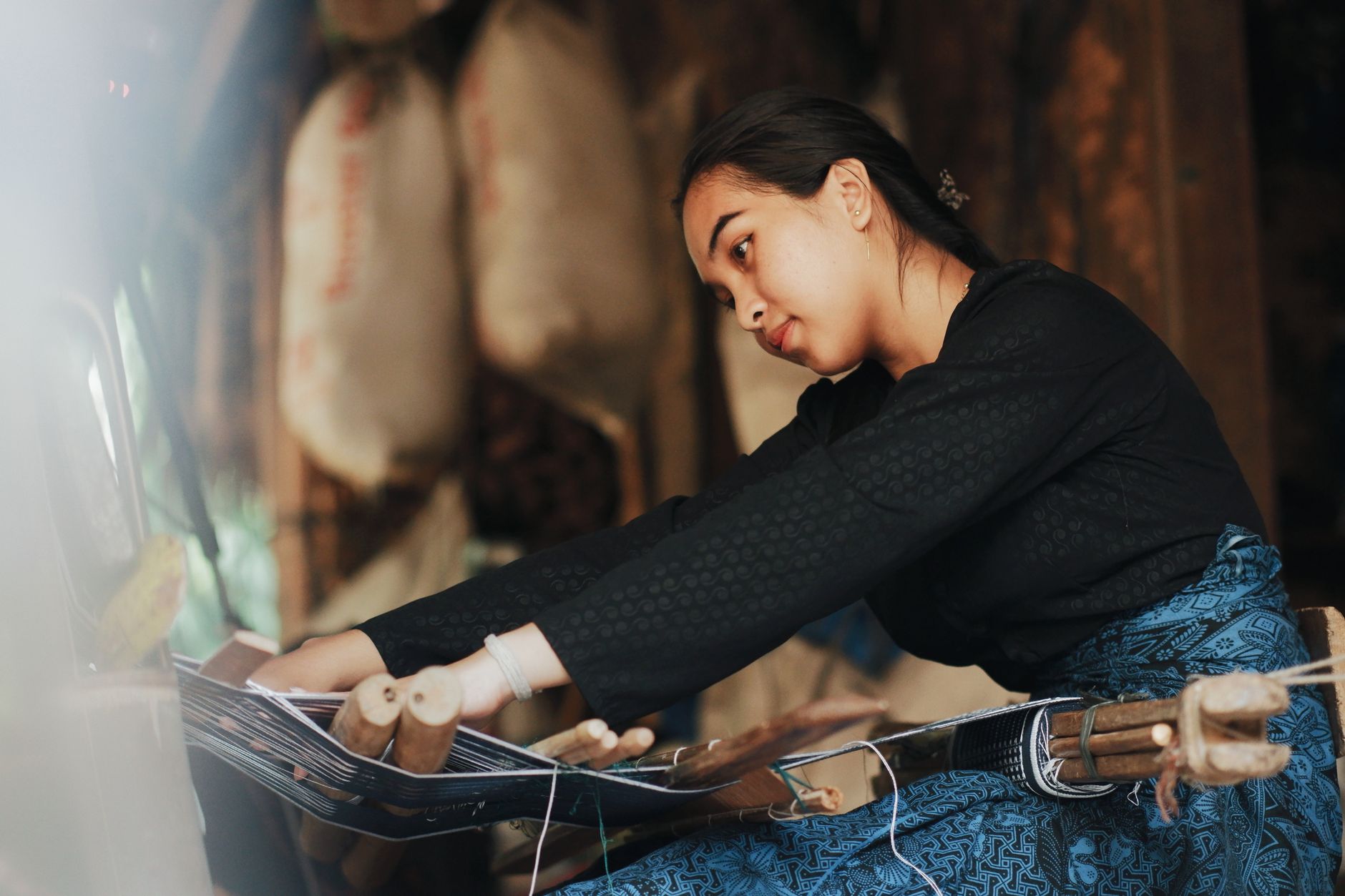 Seorang wanita dengan terampil menenun kain tradisional di atas alat tenun di Banten, Indonesia.