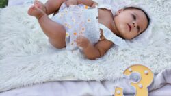 Bayi menggemaskan berbaring di atas selimut di luar ruangan, merayakan ulang bulan ketiga.