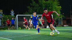 Cetak gambar dinamis pemain sepak bola yang bersaing dalam pertandingan malam di lapangan rumput.
