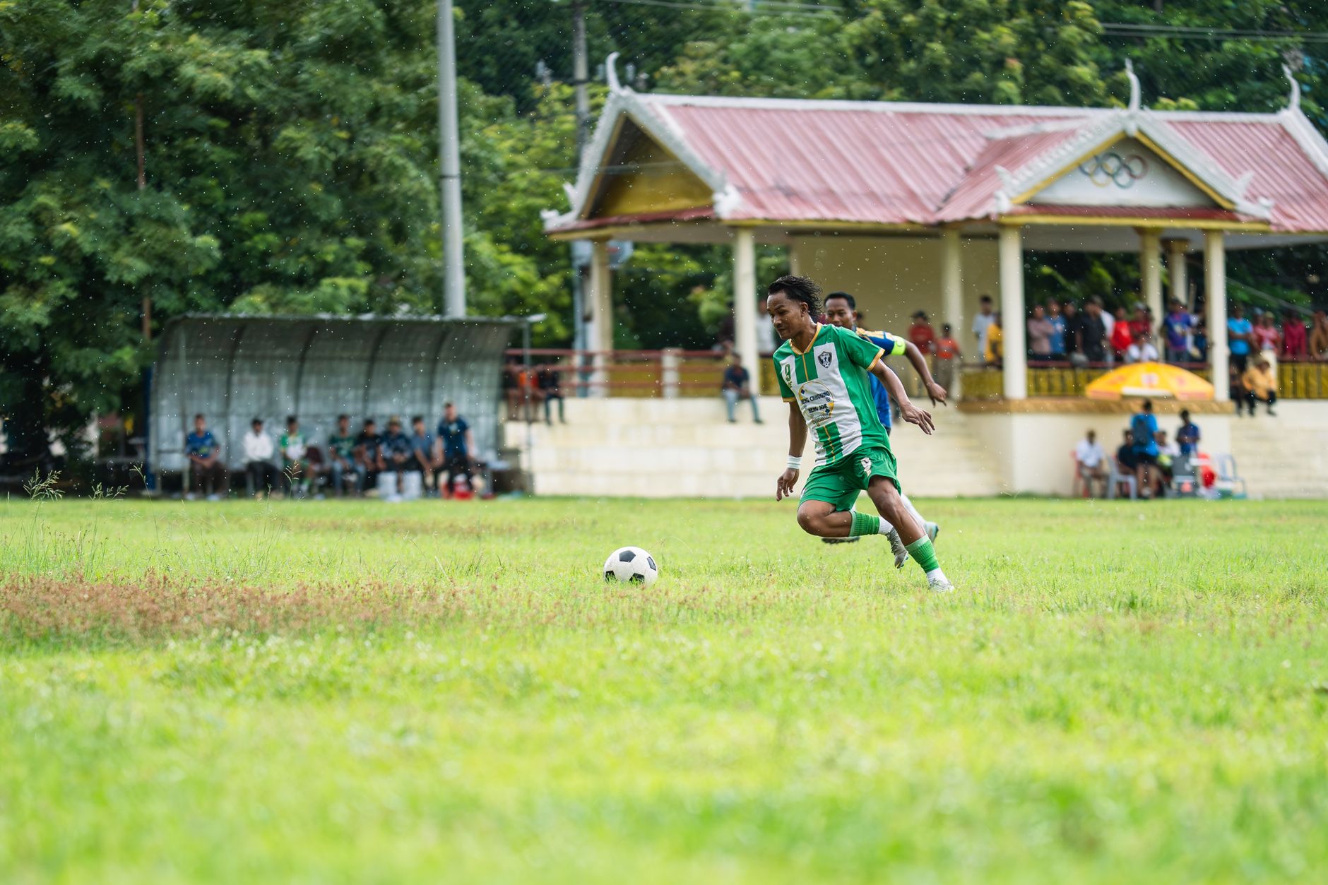Pemain sepak bola muda beraksi di hari hujan selama pertandingan luar ruangan lokal.