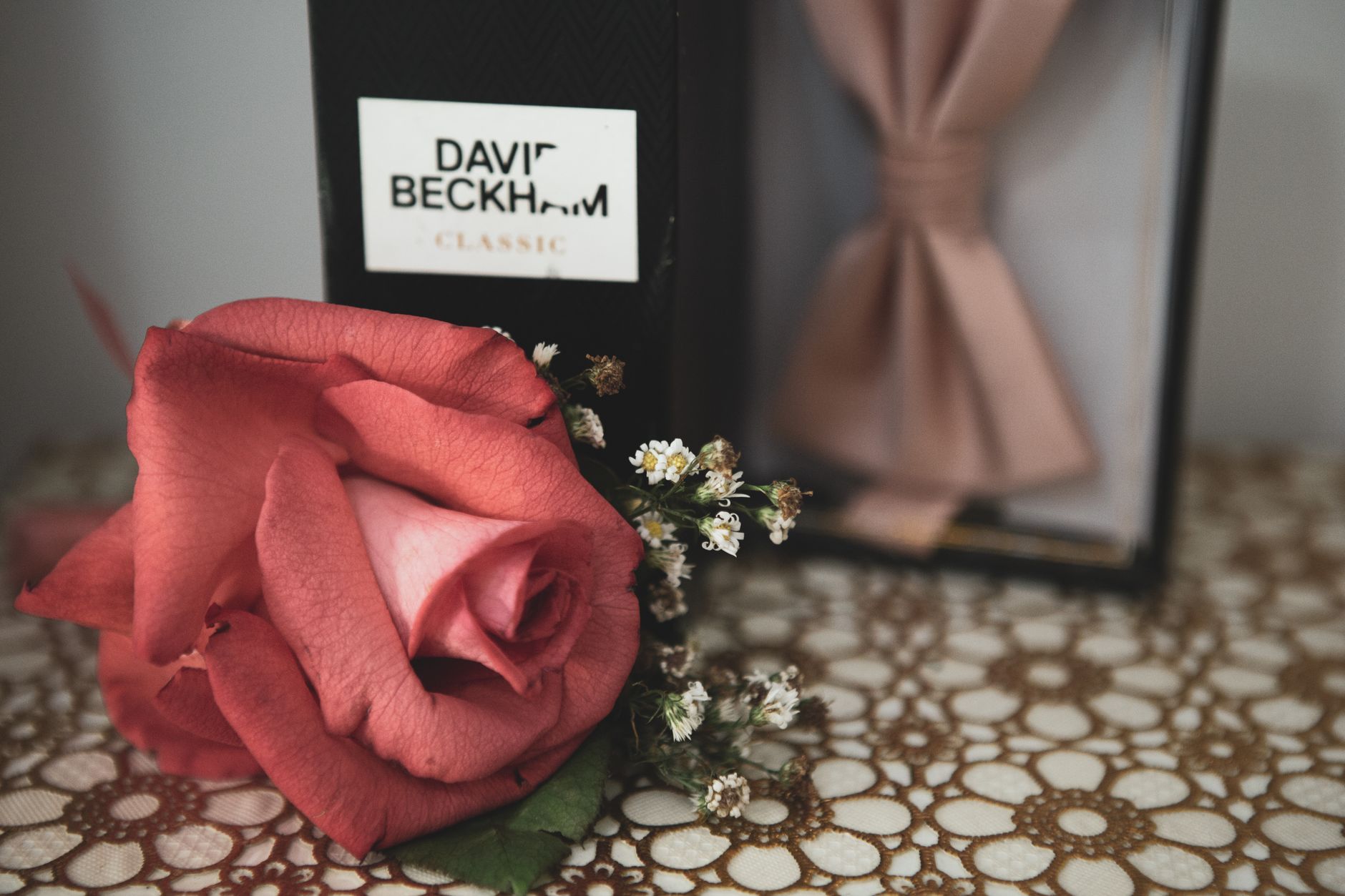 Mawar merah dengan parfum David Beckham dan pita merah muda di atas renda. Sempurna untuk dijadikan hadiah.