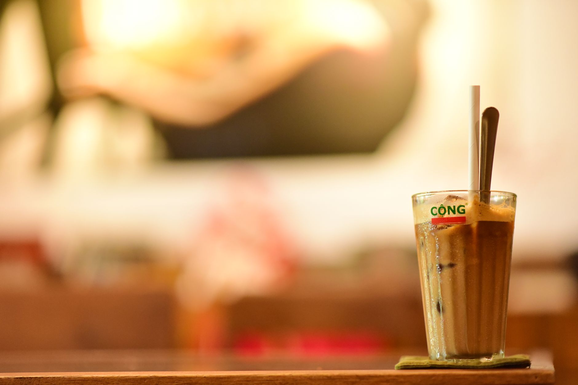 Kopi es yang menyegarkan disajikan dalam gelas dengan sedotan dan sendok di kafe Vietnam yang nyaman.