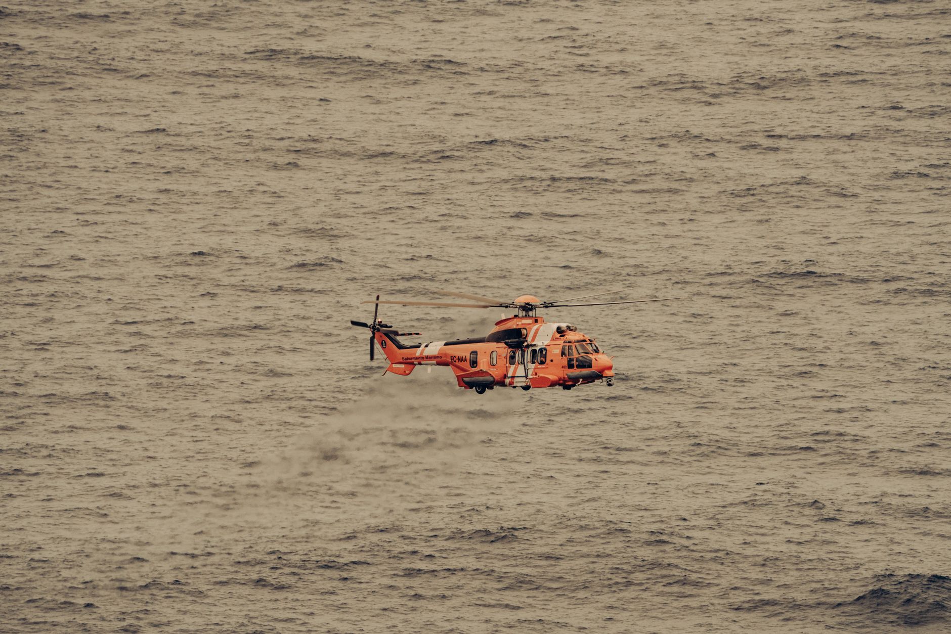 Pemandangan udara dari helikopter penyelamat yang terbang di atas lautan yang luas, diabadikan saat sedang terbang.
