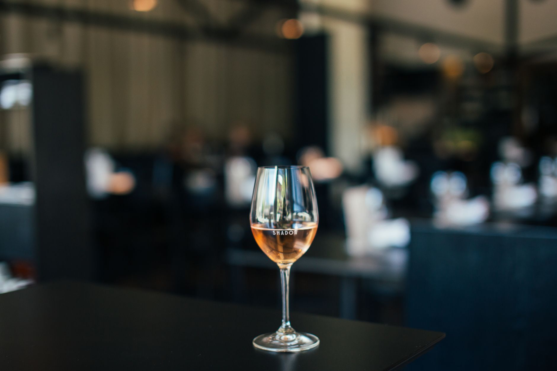 Sebuah gelas anggur dengan rosé di meja di restoran modern yang chic, menciptakan suasana mewah.