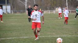 Pemain sepak bola berlari dengan fokus selama pertandingan luar ruangan yang kompetitif.
